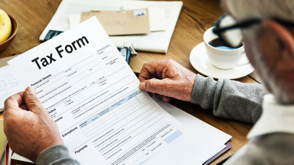 A person holding a tax form on a wooden table