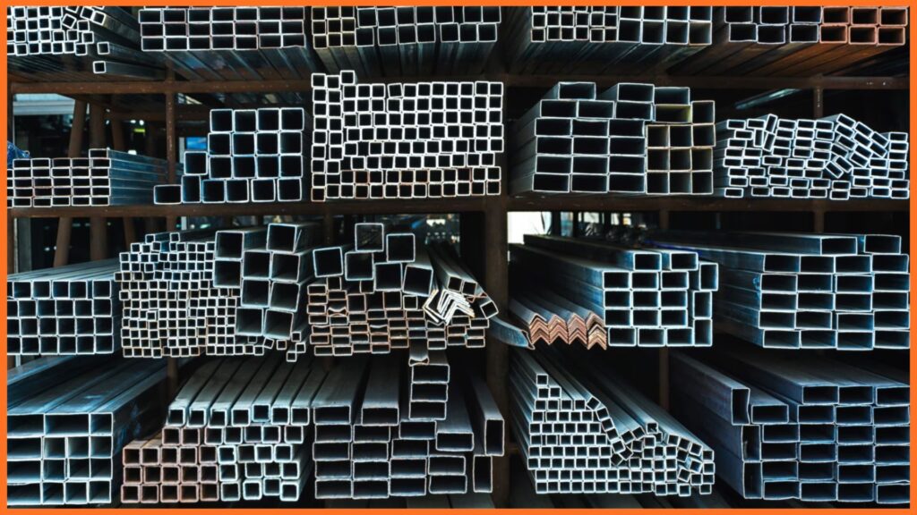 Warehouse shelves stacked with square, rectangular, and angle steel tubing in various sizes